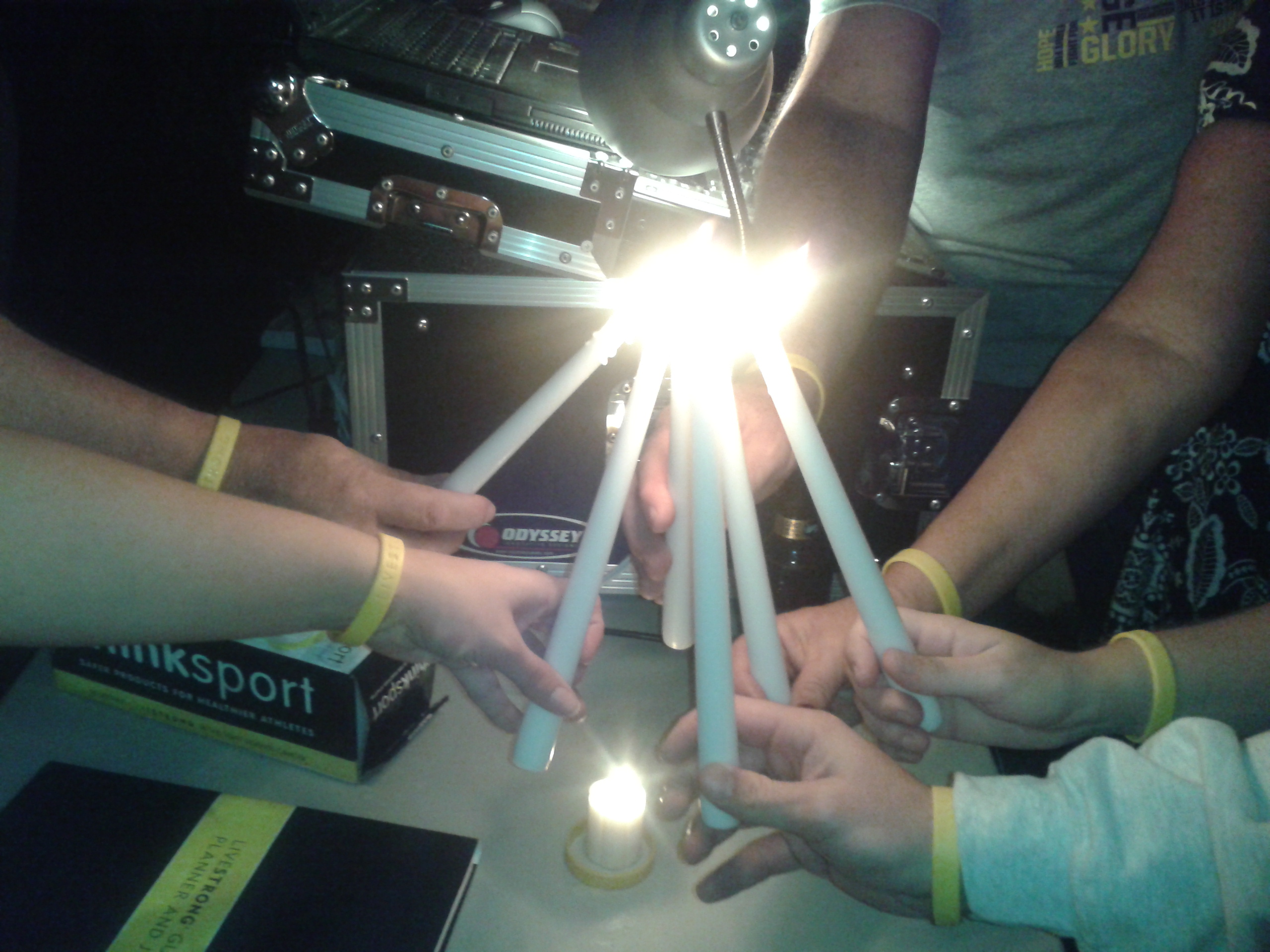 Multiple hands holding white candles joined in a circle